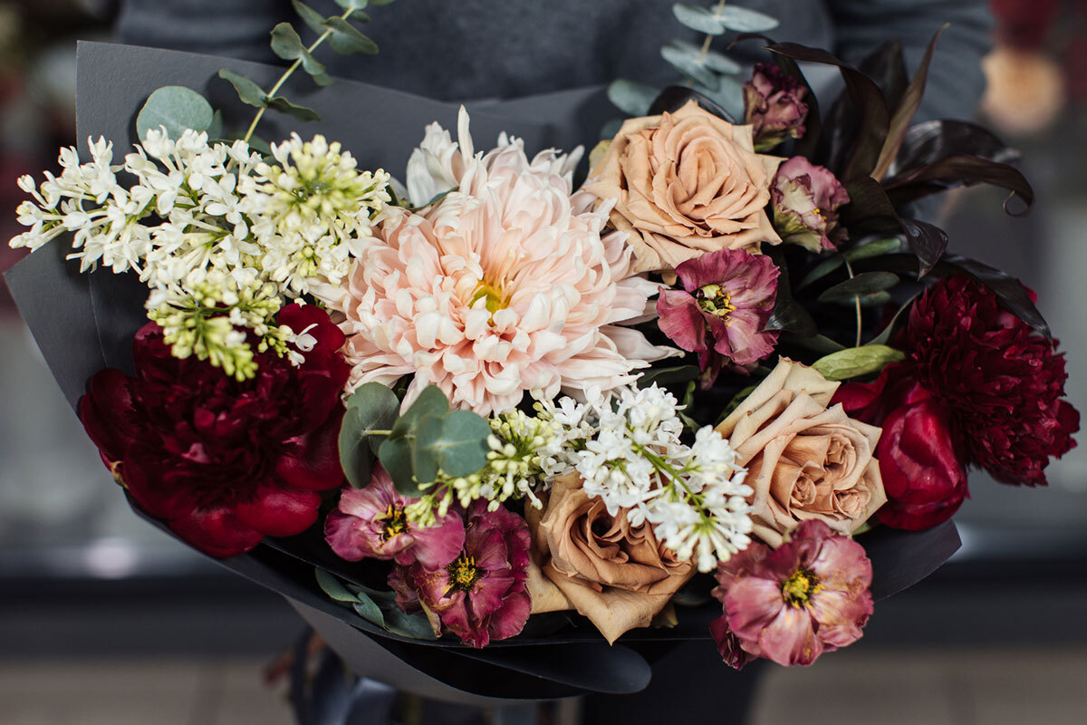 A woman holding a bouquet wraps with black paper