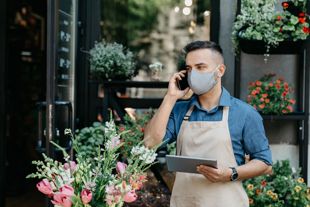 A flowershop attendant confirming all the orders from client.