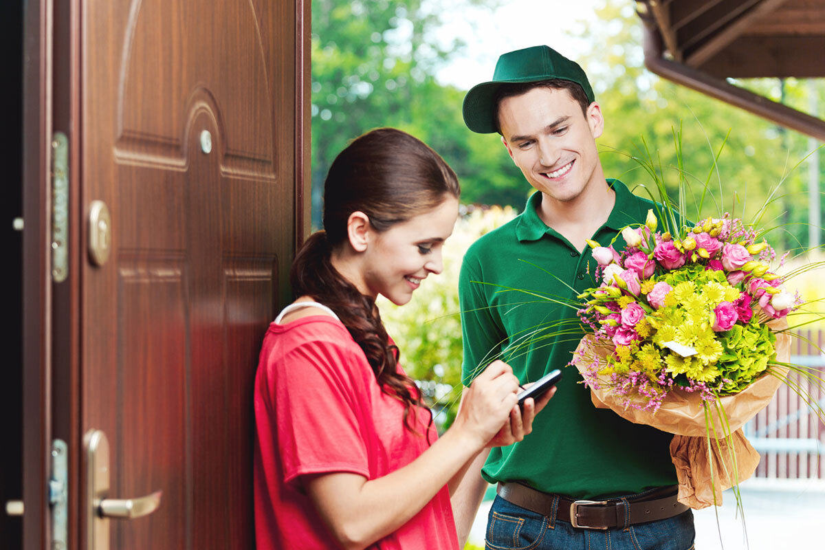 A young woman sign for receiving her order of bouquet of flower.