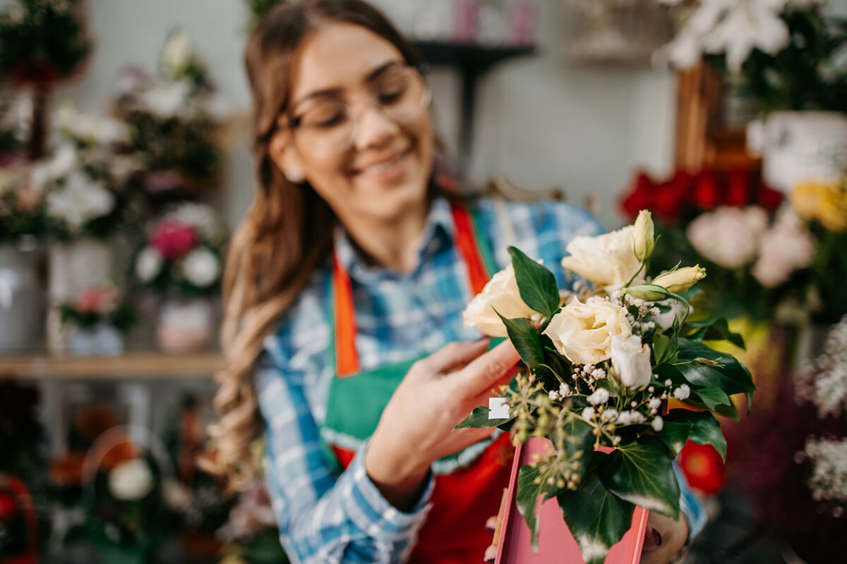 Young woman working in flowershop, preparing for orders