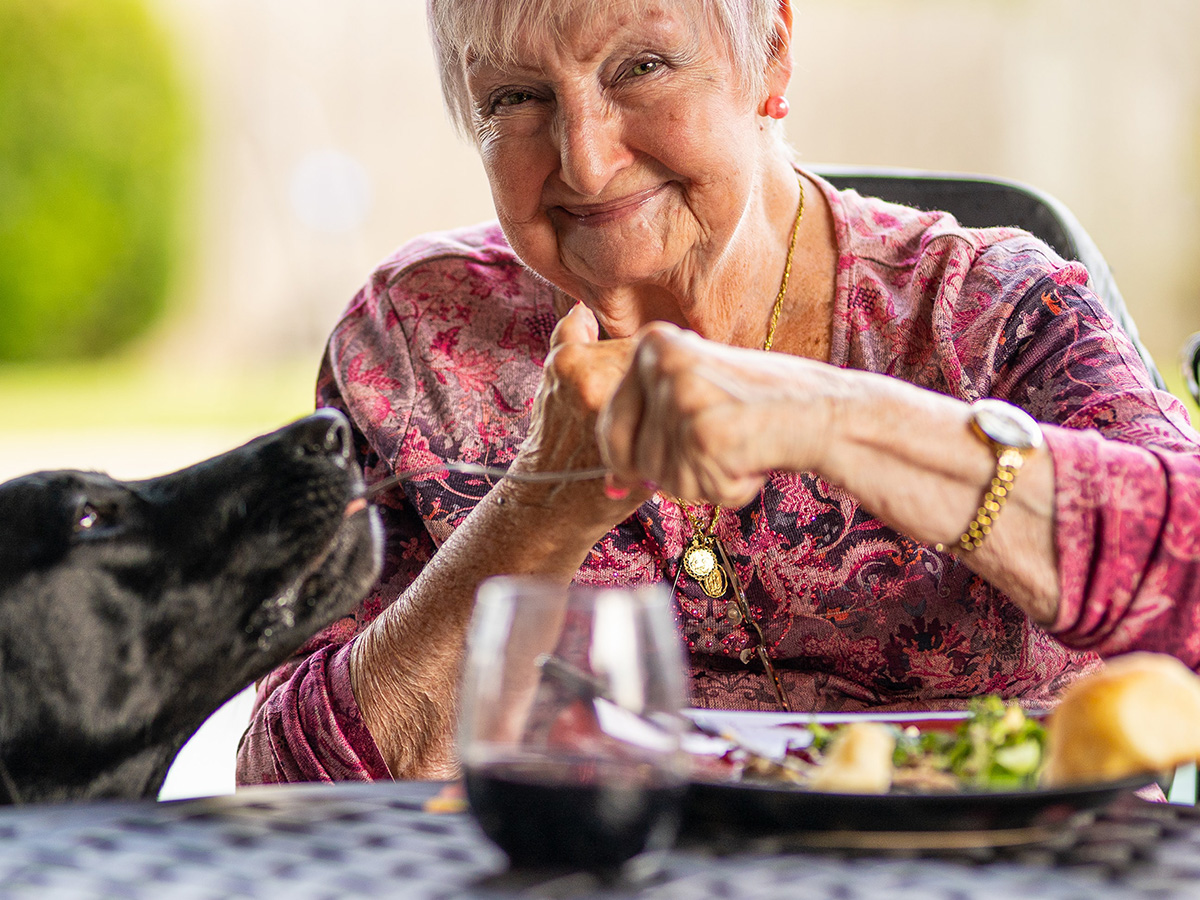 A senior citizen smiling and eating.