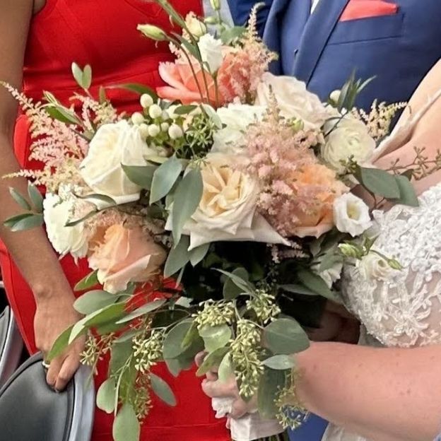 Bridal bouquet featuring peach and white roses with soft greenery, arranged in a round, elegant style.