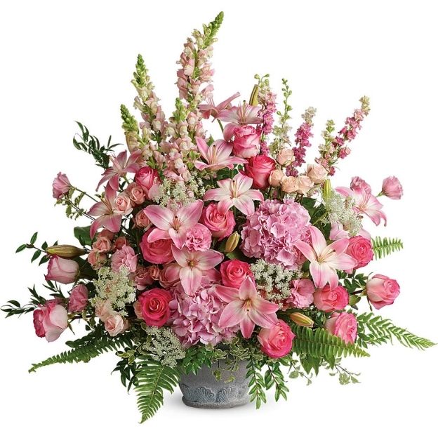 Large floral arrangement with pink lilies, roses, carnations, and greenery in a gray vase.