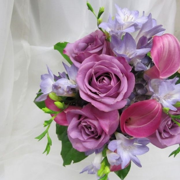 Romantic bouquet of purple roses and matching flowers in varying shades, arranged with lush foliage for a soft, rich look