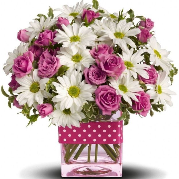 A mix of daisies and pink spray roses in a polka dotted vase arrangement.