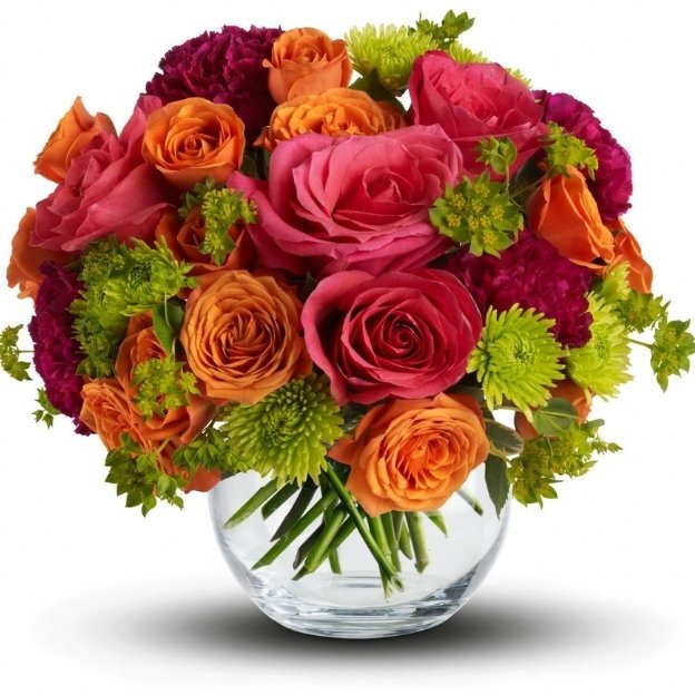 Bright floral arrangement featuring pink and orange roses with green accent blooms in a clear glass vase on a white background.