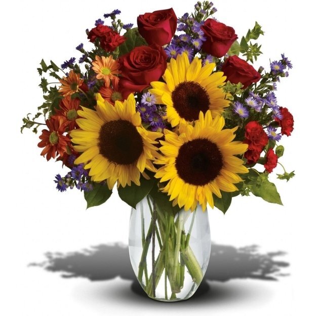 Bright mixed floral arrangement featuring sunflowers, red roses, and seasonal blooms in a clear glass vase.