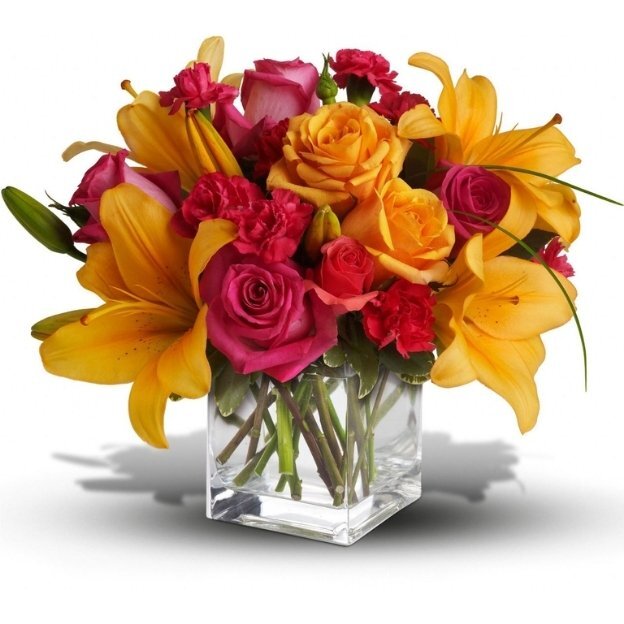 Bright floral arrangement featuring yellow lilies, pink roses, and mixed blooms in a clear square glass vase.