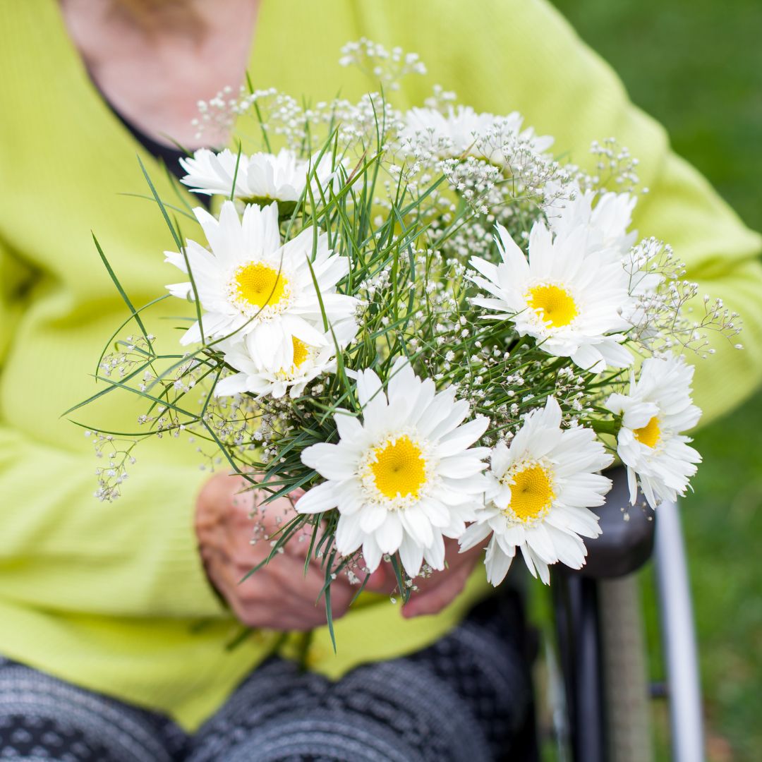 person in a nursing home holding flower arrangement